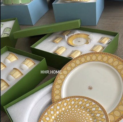 A gold-rimmed HHR Home dinner plate and napkin ring set, boxed